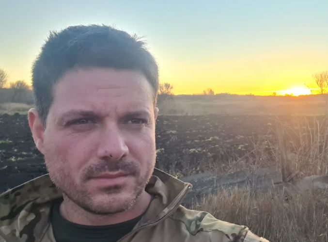 Porträt von Jerome, der in Uniform auf einem Feld in der Ukraine steht