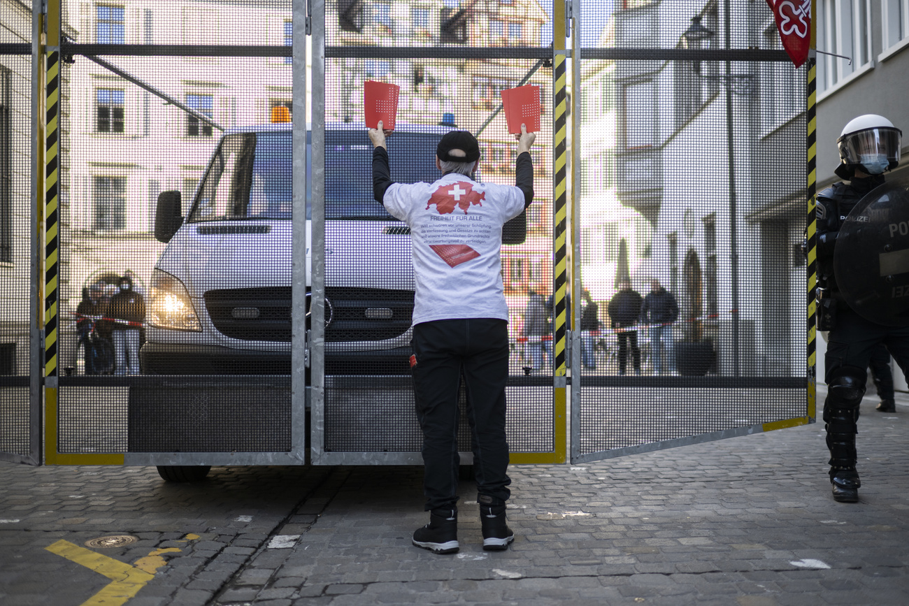 Freiheitstrychler steht vor einer Polizeiabsperrung