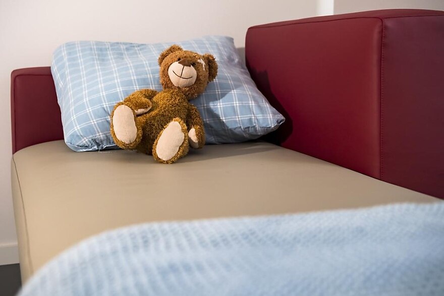 Bett mit einem Teddybär auf dem Kopfkissen