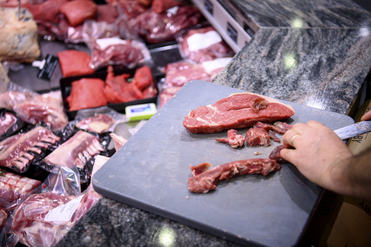 Açougueiro corta carne em um supermercado.