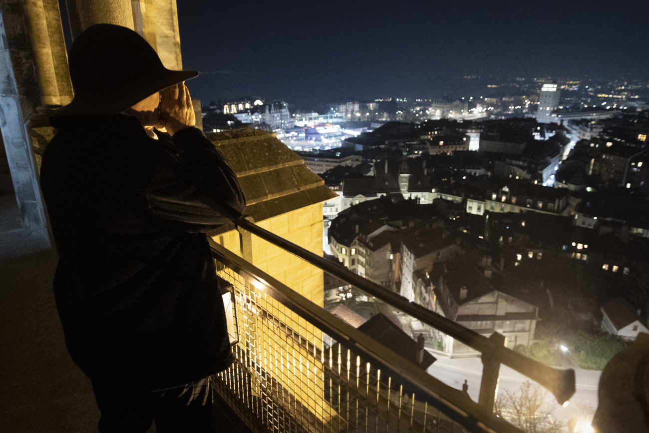 Man on top of Lausanne cathedral in the night