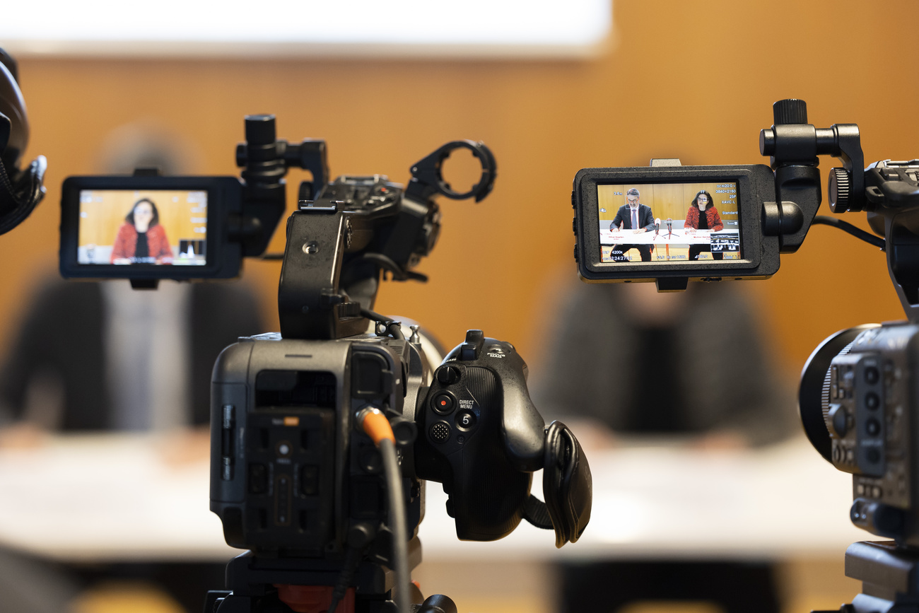 Media cameras filming FINMA executives at a press conference
