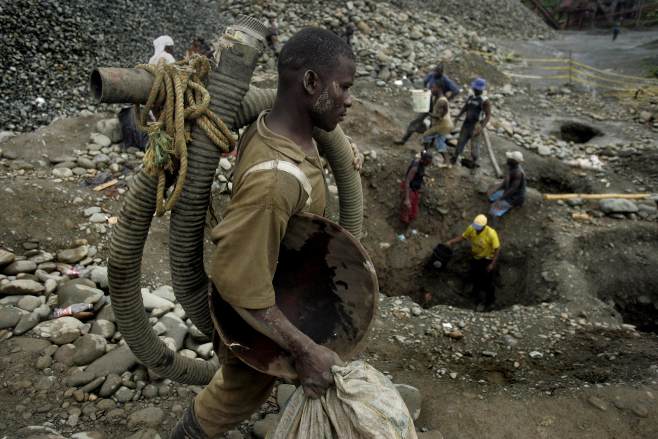 A man carries equipment as others pan for gold along the Dagua River in Zaragoza, Colombia.