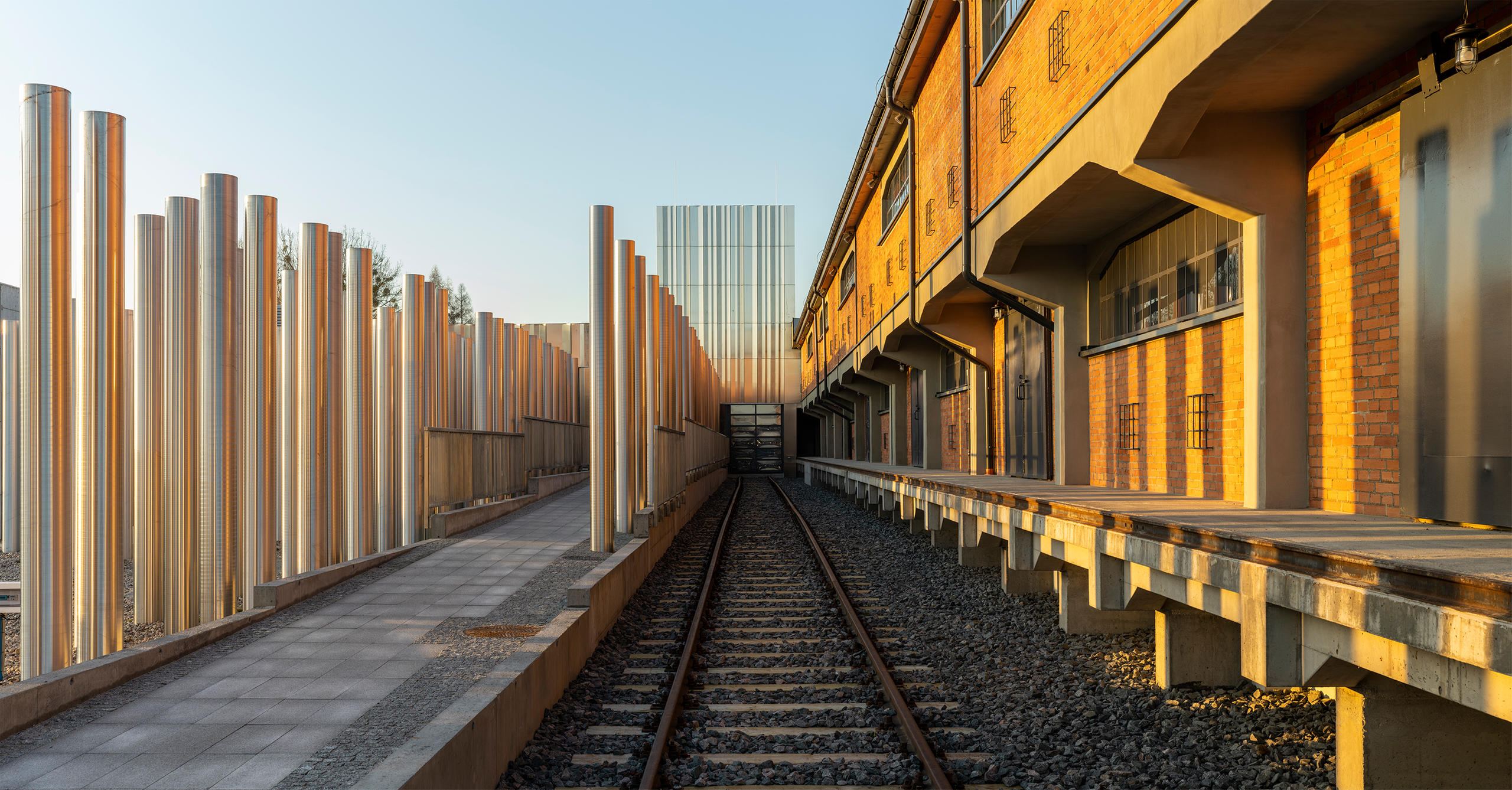 Metal columns installation, railway line, and old brick building