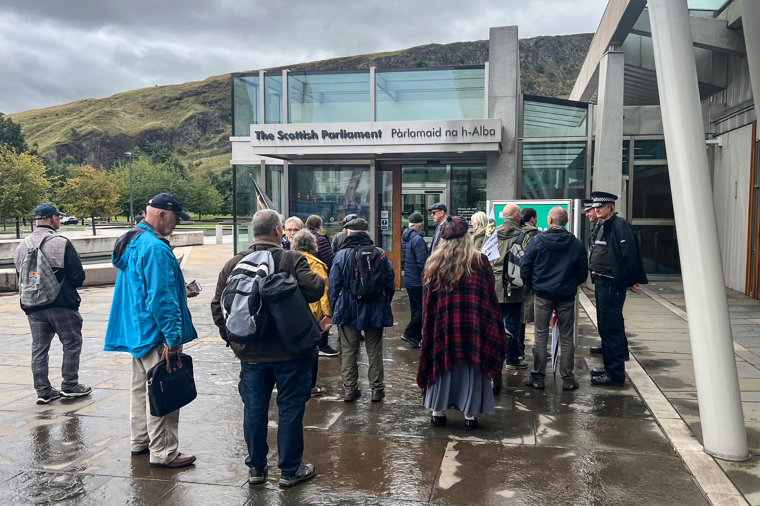 El Parlamento Escocés en Edimburgo y un grupo de personas bajo la lluvia.