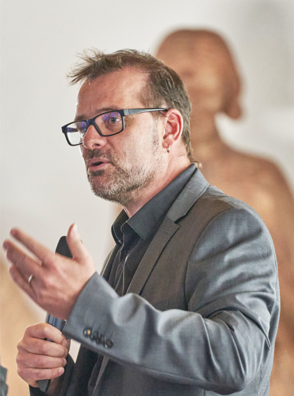 Homme barbu à lunettes parlant avec un micro