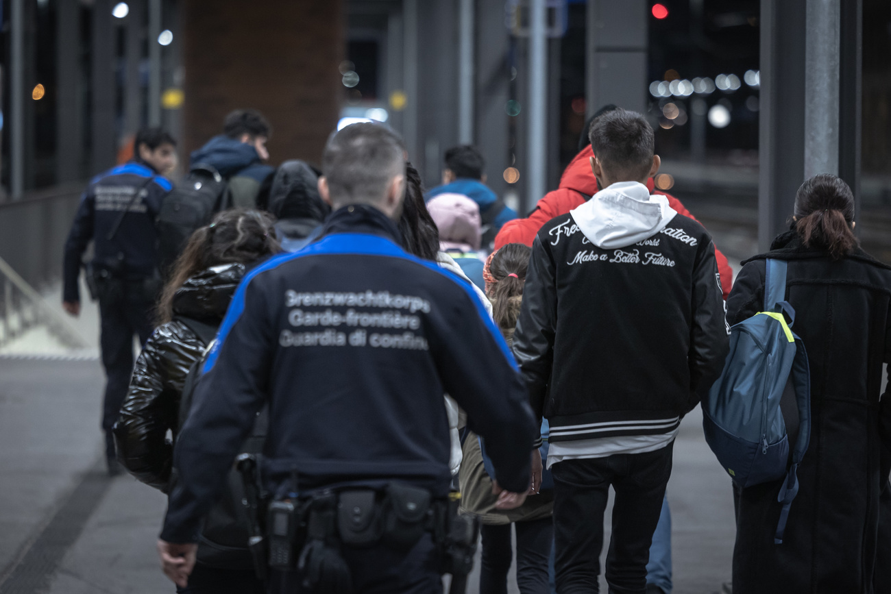 Guardie di confine alla prese con migranti alla stazione di Chiasso.