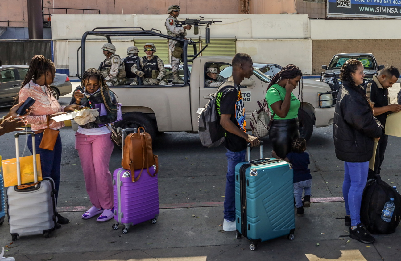 Migrants queue to cross Mexican border into the United States