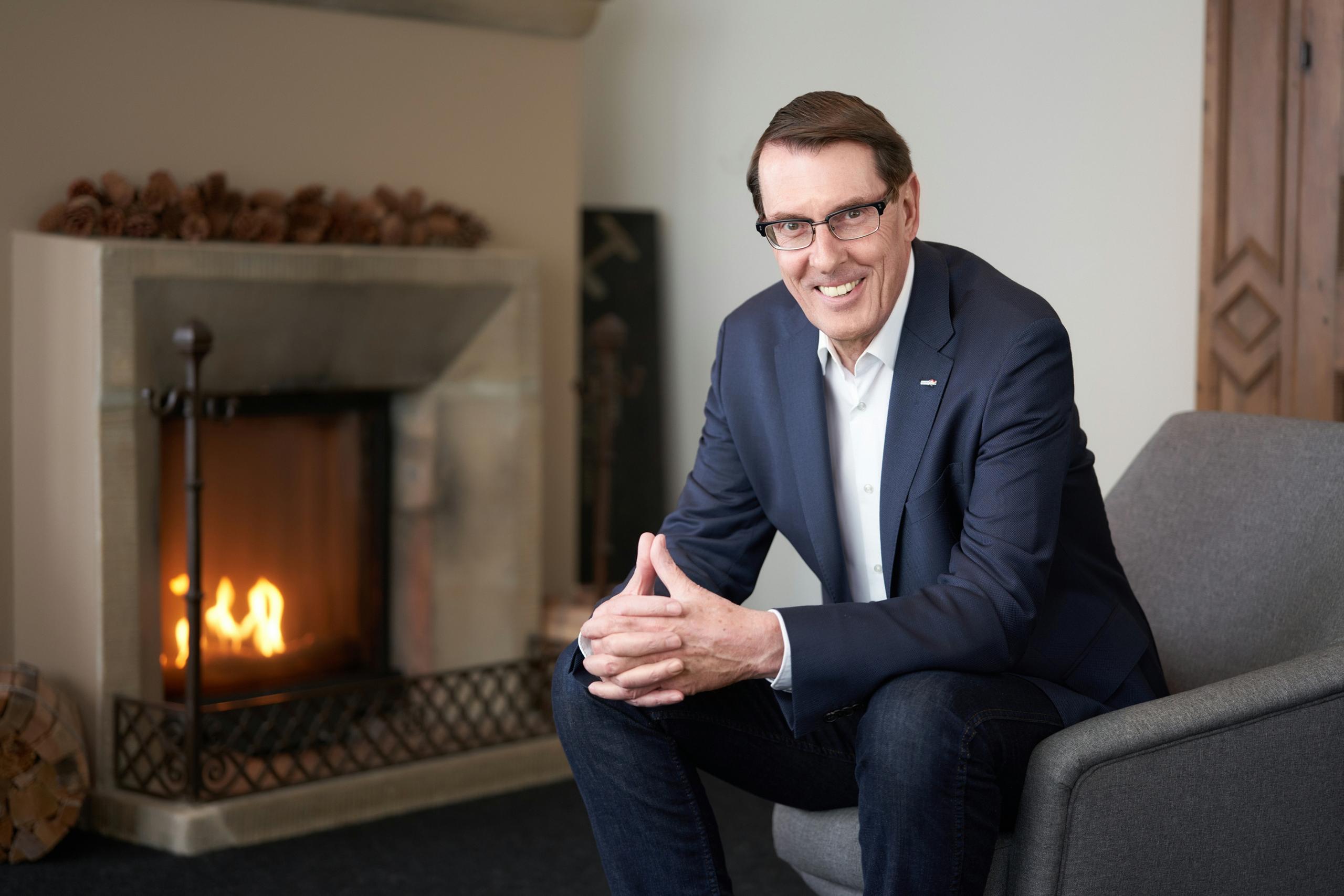 Andreas Züllig en un sillón y detrás una chimenea en lo que parece un hall de hotel