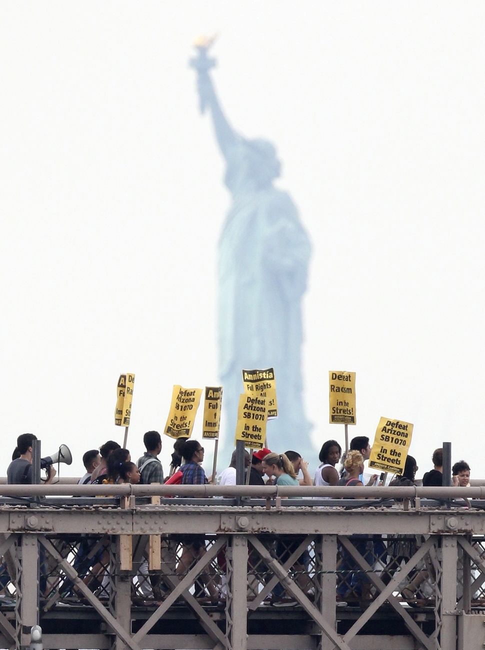 Manifestazione in difesa dei migranti sotto la statua della libertà a New York.