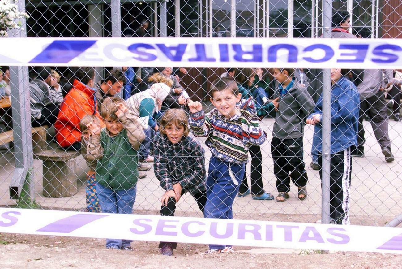 bambini dietro una rete metallica
