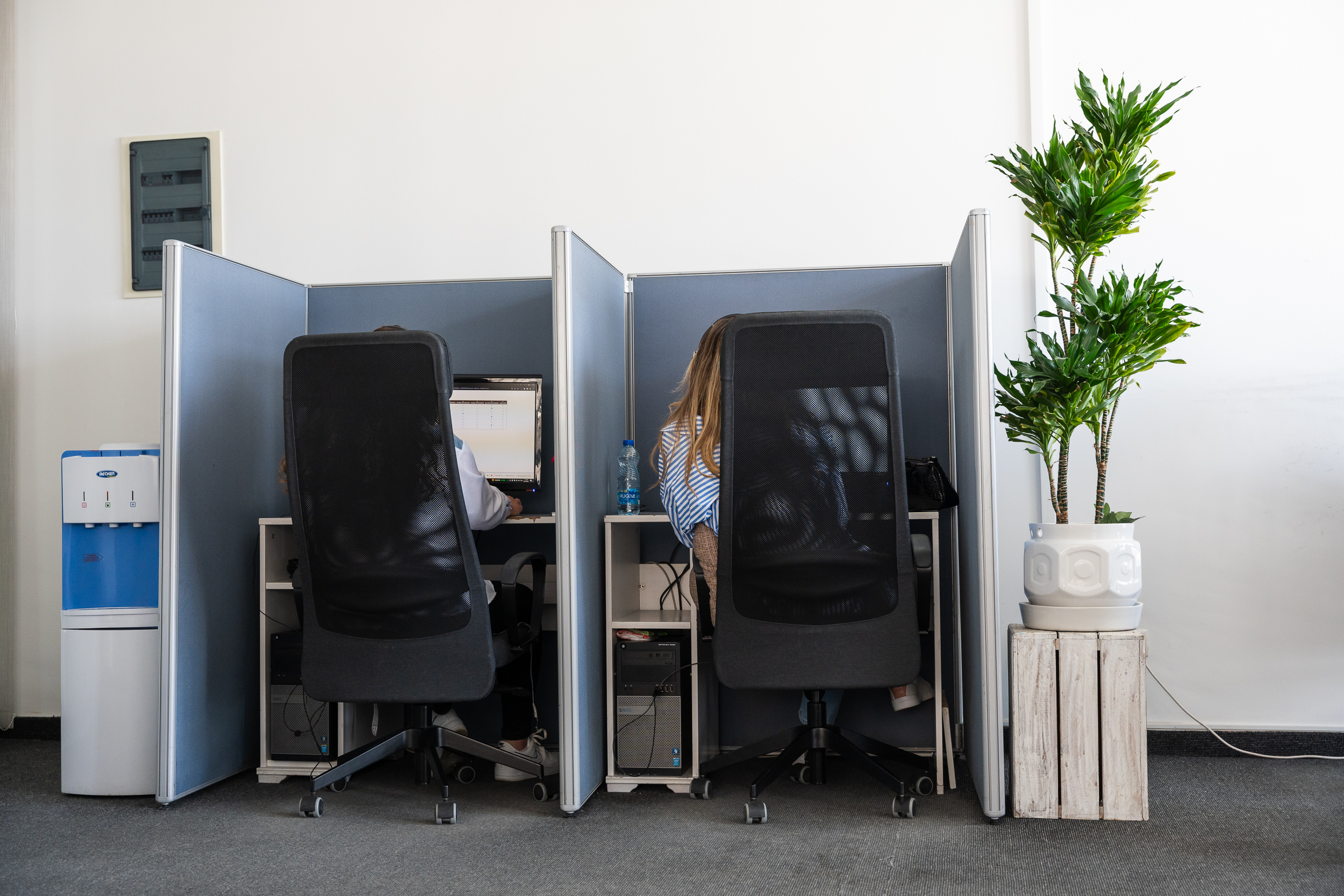 oficina de trabajo (dos mesas con dos ordenadores y dos personas con auriculares trabajando)