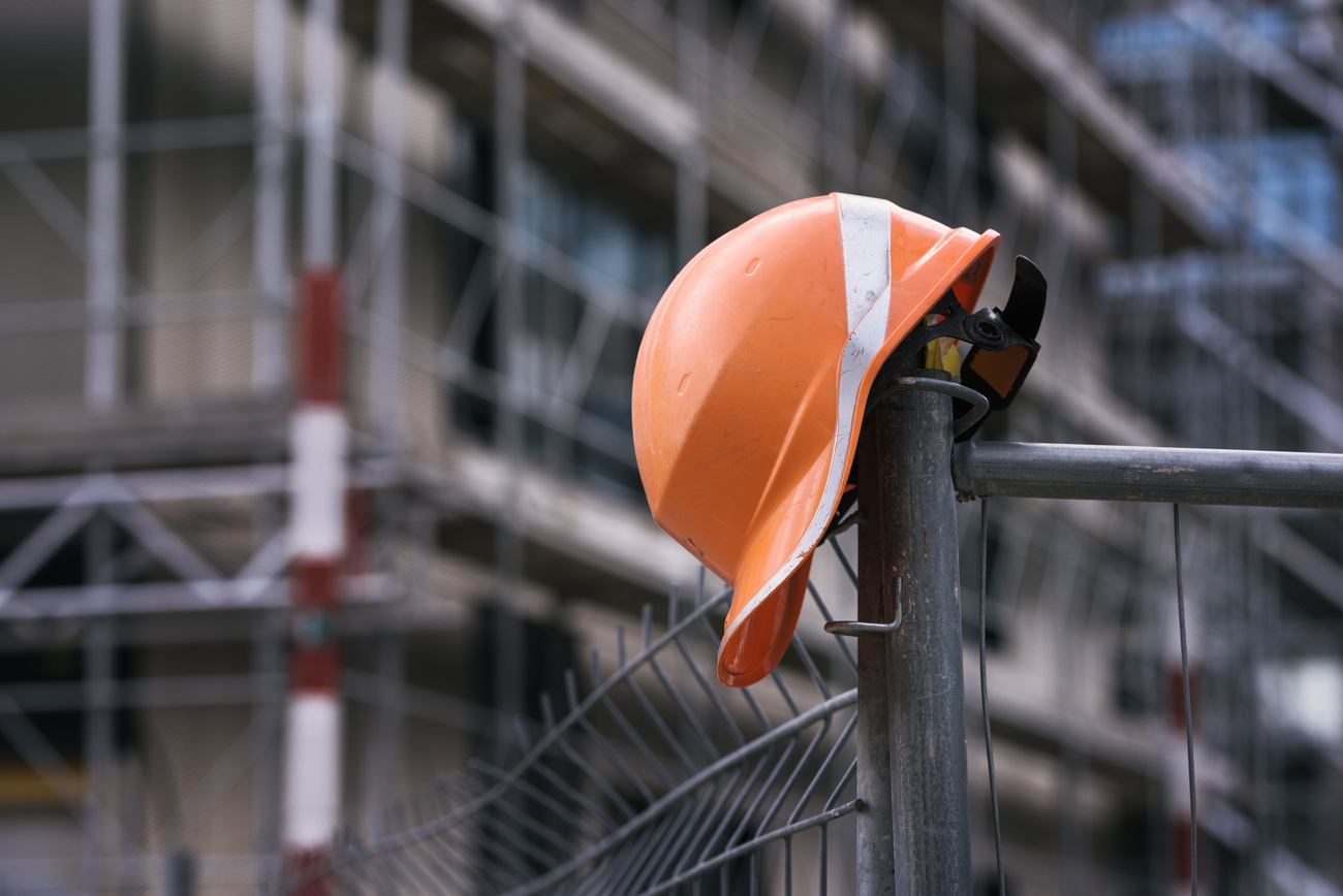 Un casco di protezione per operai appoggiato ad un impalcatura di un cantiere.
