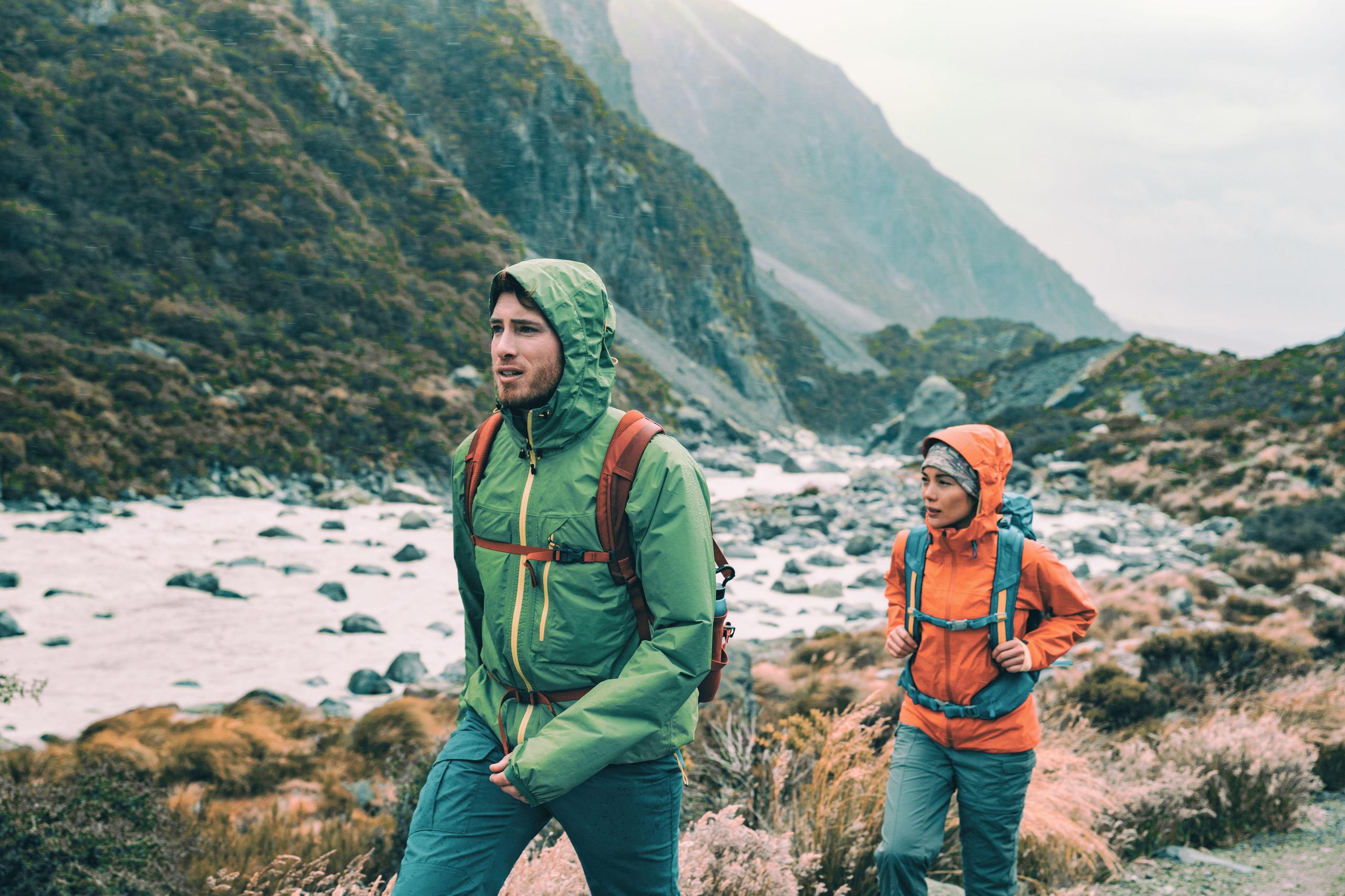 dos personas con ropa de montaña caminando bajo la lluvia