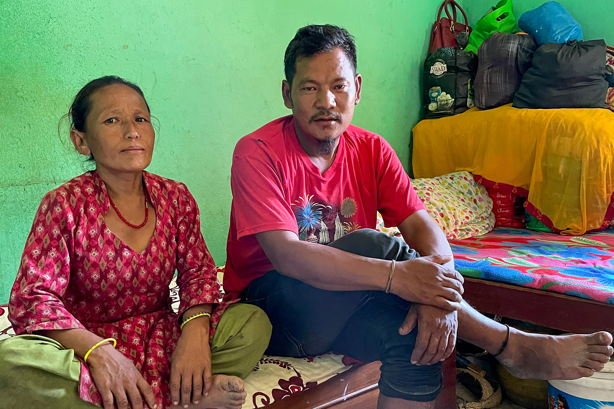 Maili and Bahadur Tamang sitzen auf einer Matratze in ihrem Haus