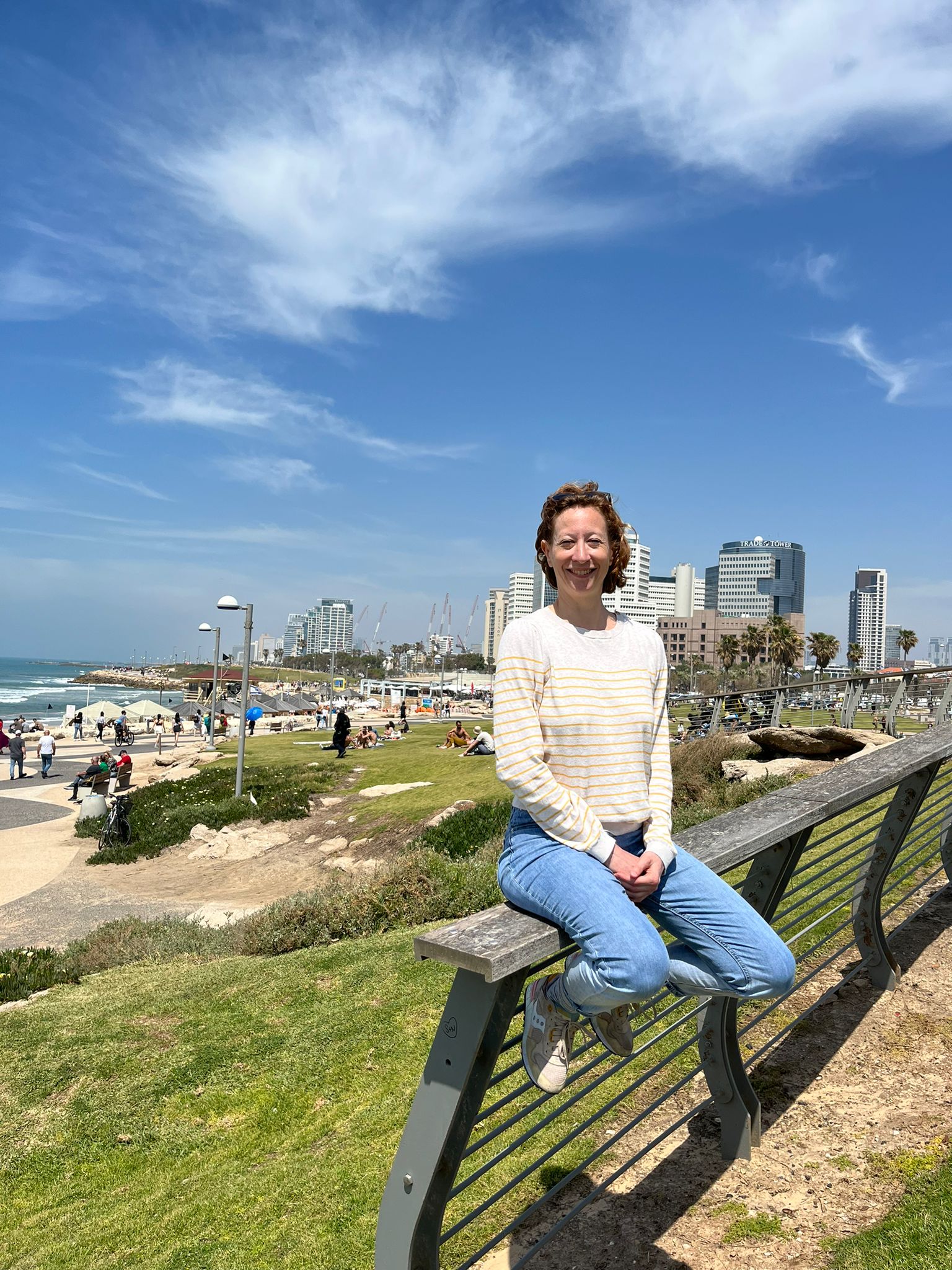 woman sitting on a railing with city in background
