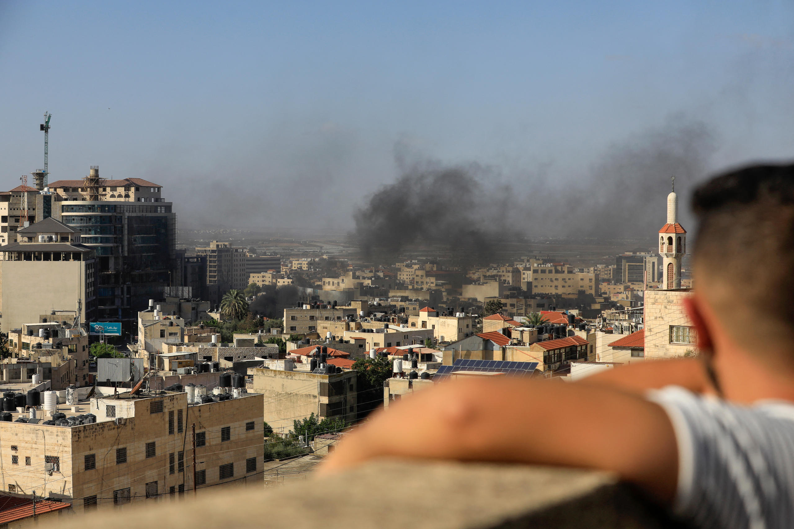 طفل ينظر إلى دخان يتصاعد في مبنى بمدينة فلسطينية