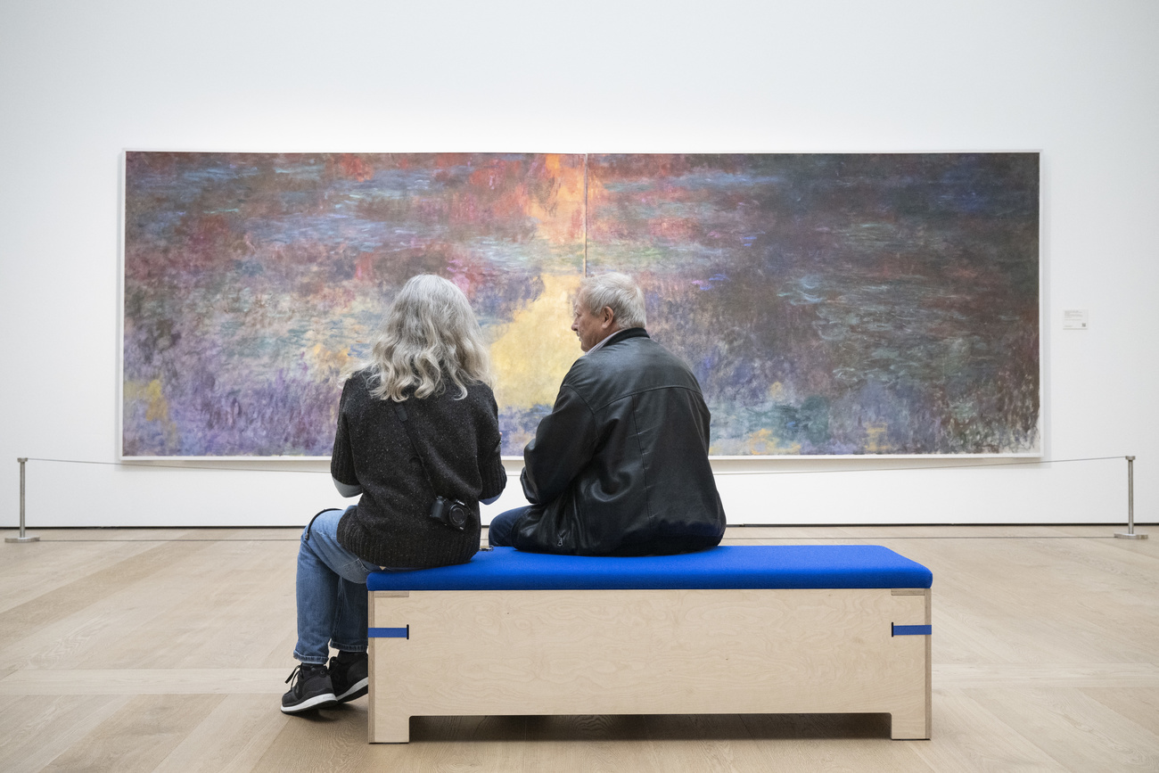 Zwei Personen auf einer Bank vor Monets breitformatigem Gemälde
