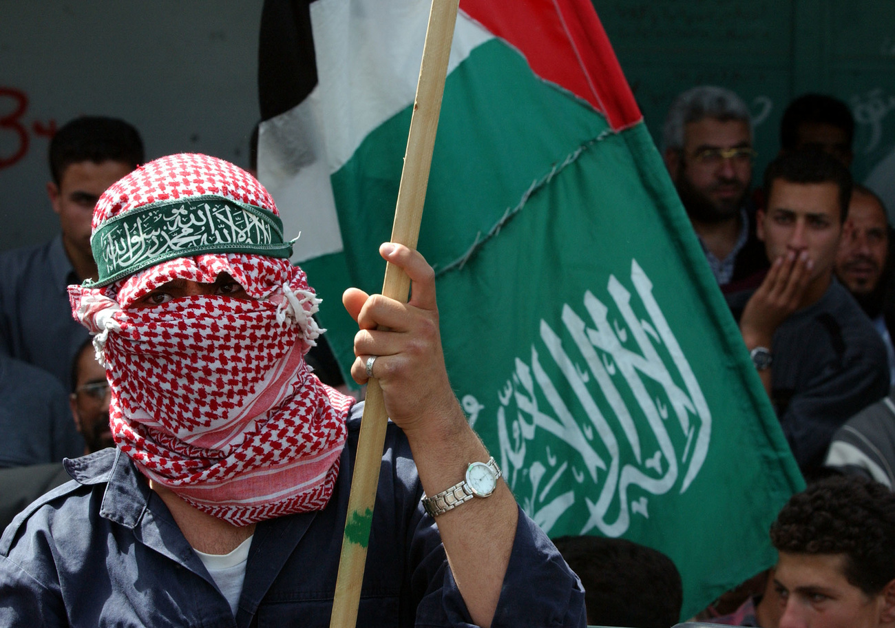 manifestante con viso ricoperto da keffiah e bandiera in mano