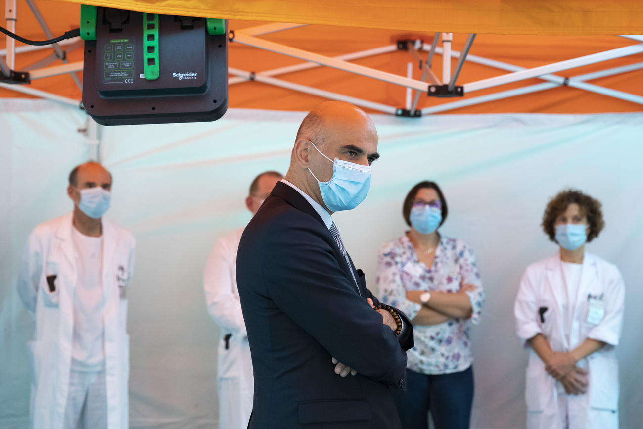 Alain Berset con mascarilla en una sala de hospital hablando con pacientes de cuidados intensivos