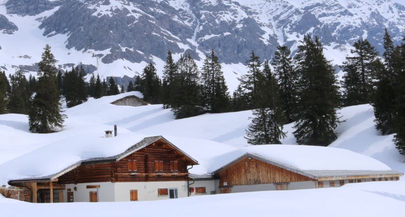 Geschlossene Alphütten auf einer Alp mit viel Schnee