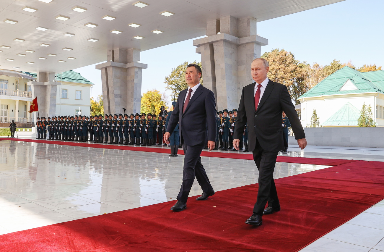 Putin läuft über einen roten Teppich, im Hintergrund stehen Soldaten Spalier.