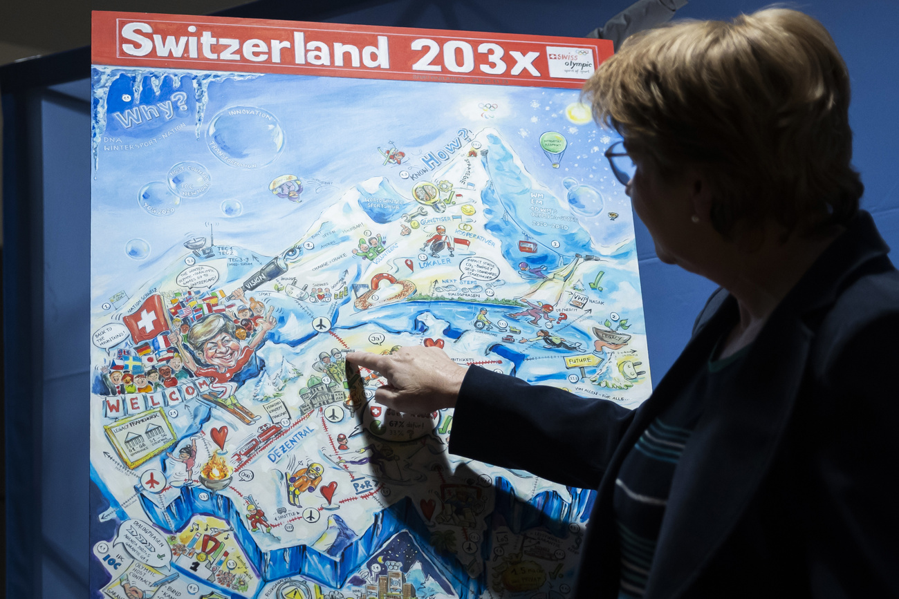 Bundesrätin Amherd zeigt auf eine Schweizer Karte, die die Olympischen Spiele zeigen