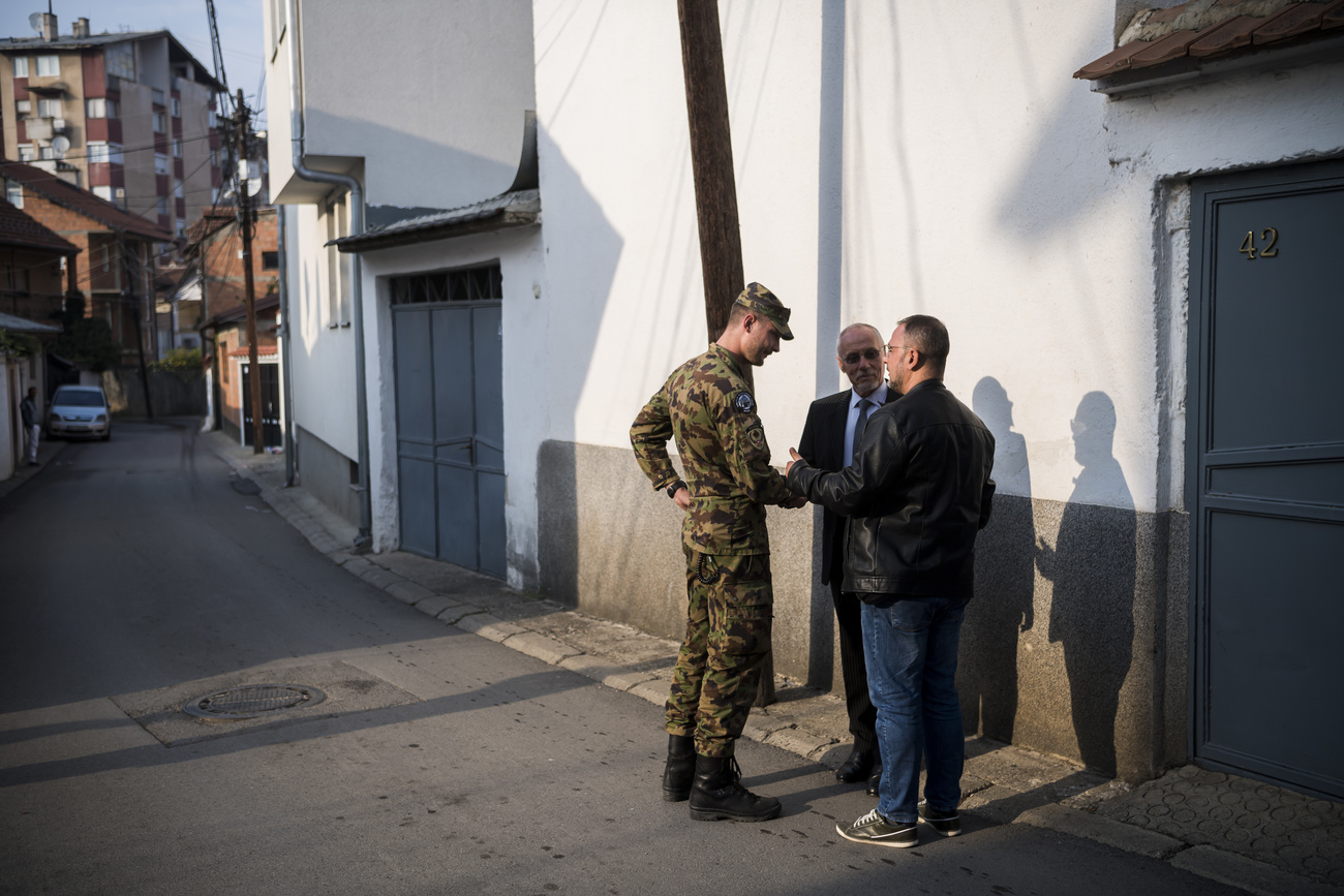 Ein Swisscoy-Soldat mit einem Übersetzer und einem Mann auf der Strasse