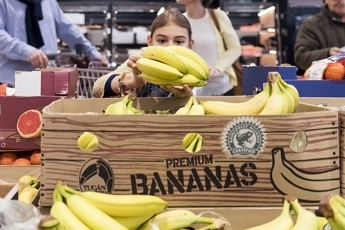 Eine Frau in einem Supermarkt nimmt Bananen aus einer Kiste