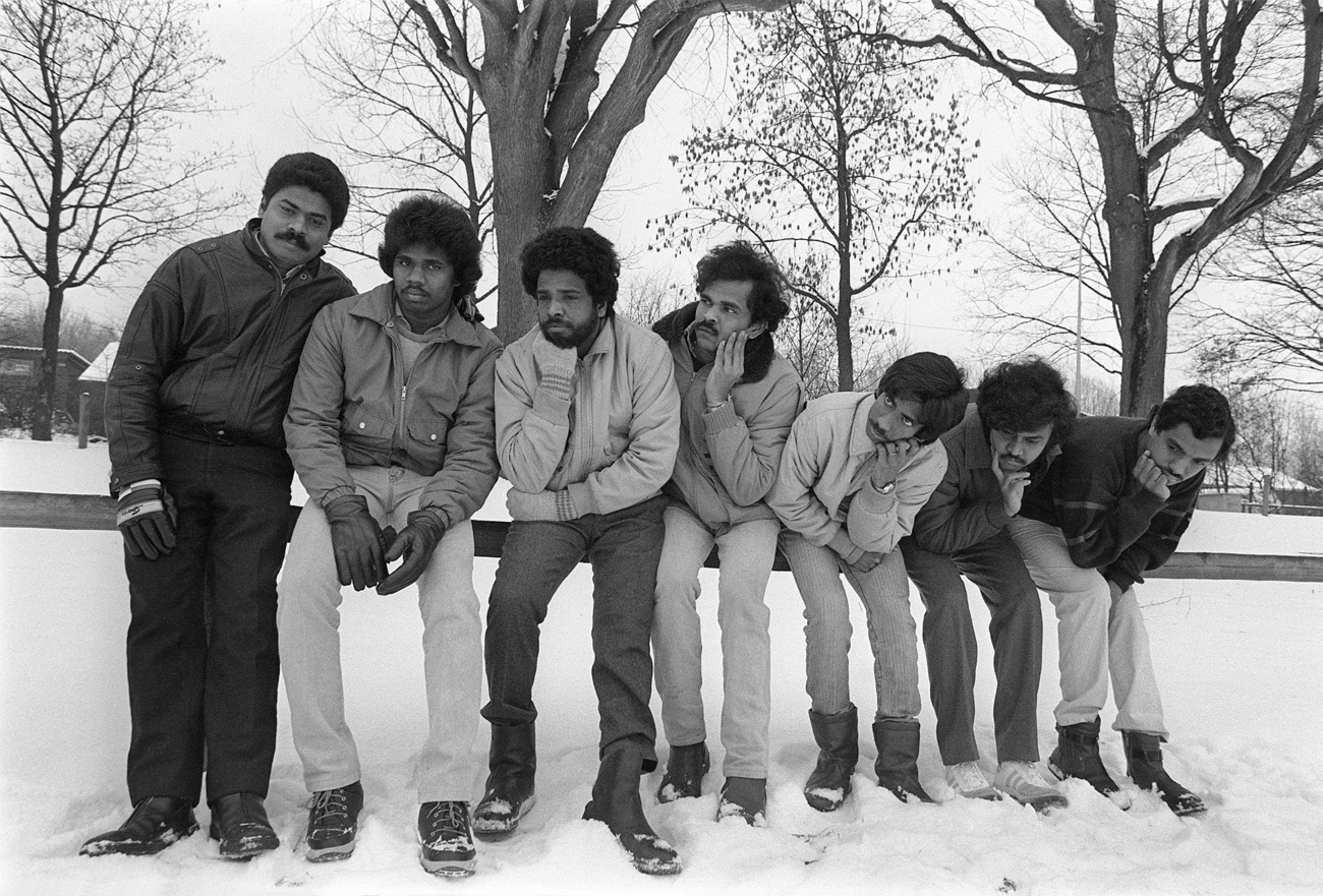 Eine Gruppe tamilischer Männer sitzen im Schnee und vertreiben sich die Zeit.