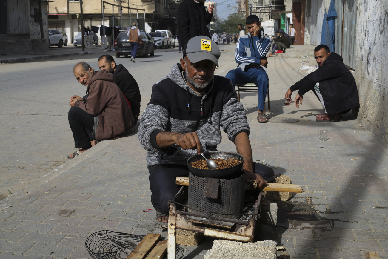 Un palestinese cucina in strada, a Rafah.