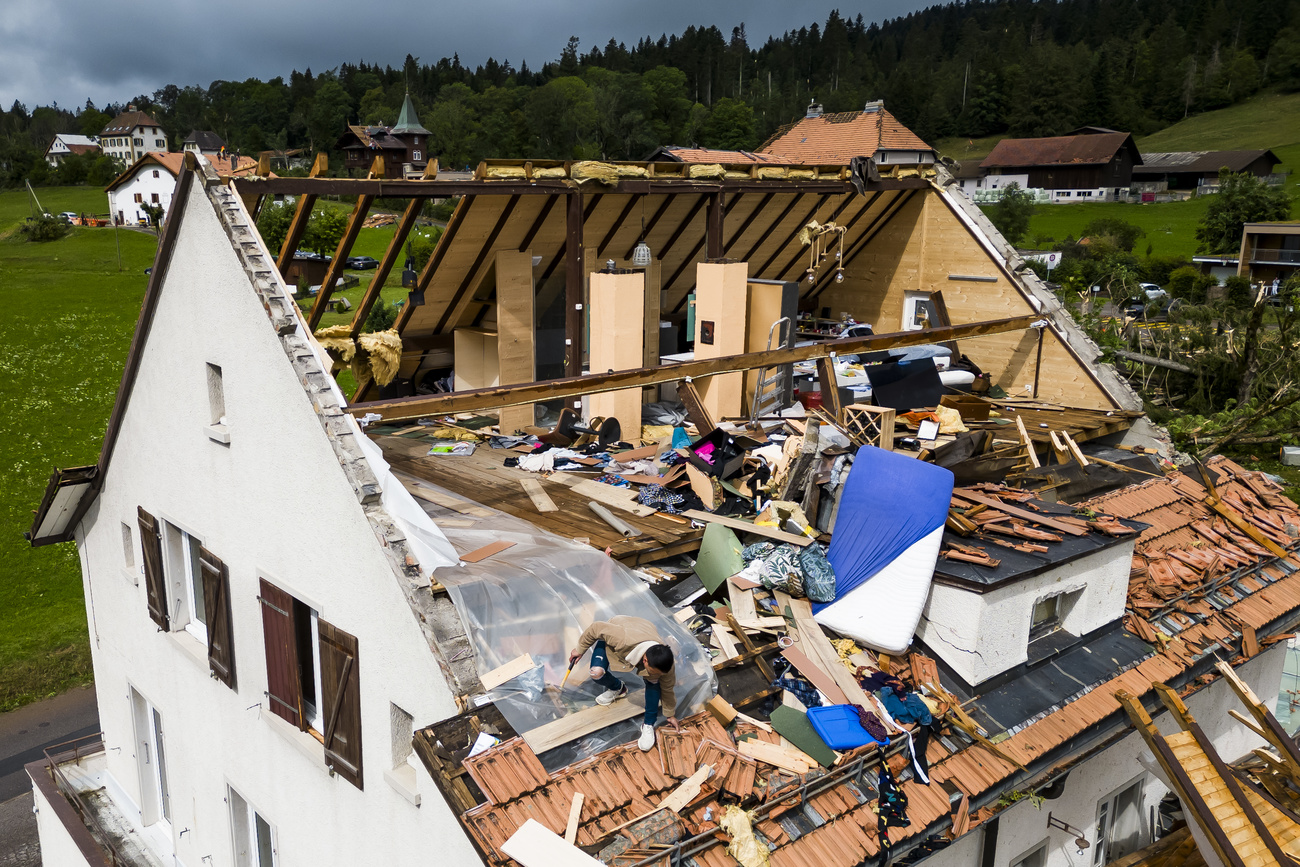 Abgedecktes Haus in Schweizer Landschaft, vom Dachstock ist nicht einmal die Hälfte übrig