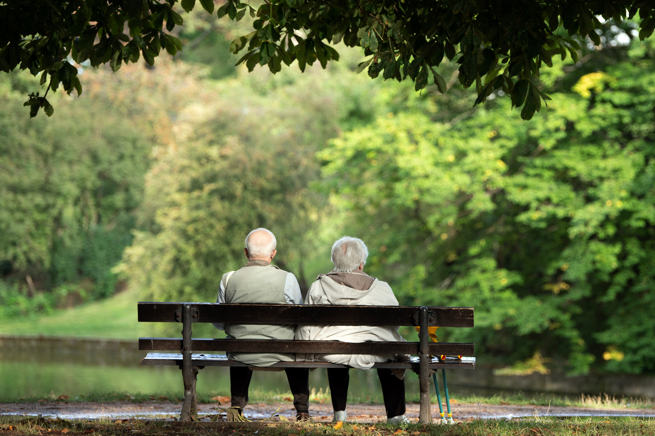 Una coppia di persone anziane sedute accanto su una panchina.