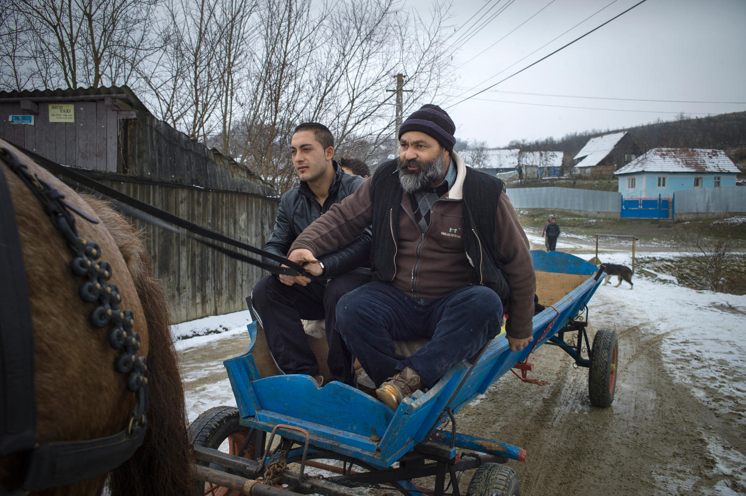 Dos hombres sentados en una carreta tiradas por un caballo