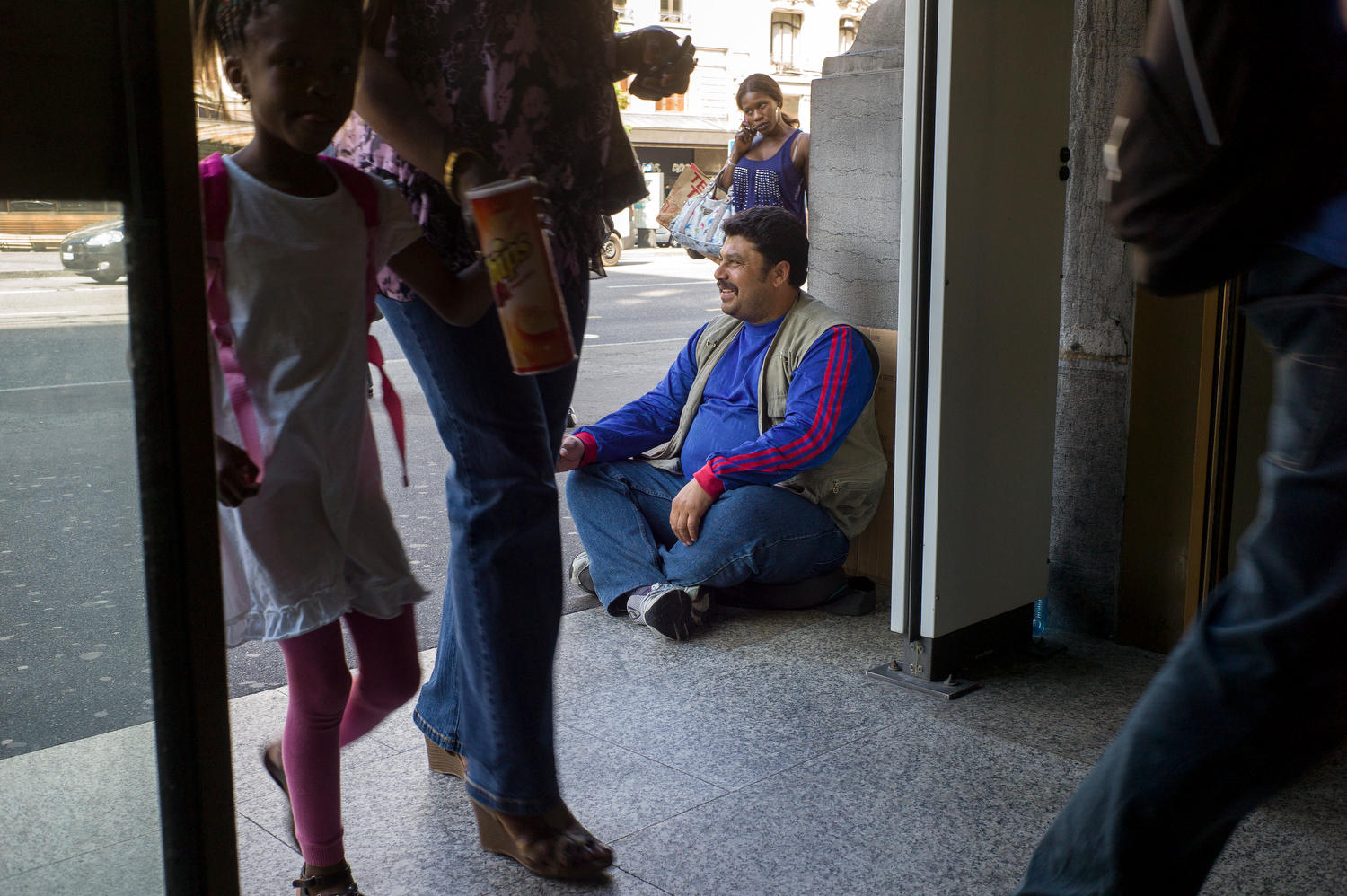 Un homme mendie assis par terre dans la rue