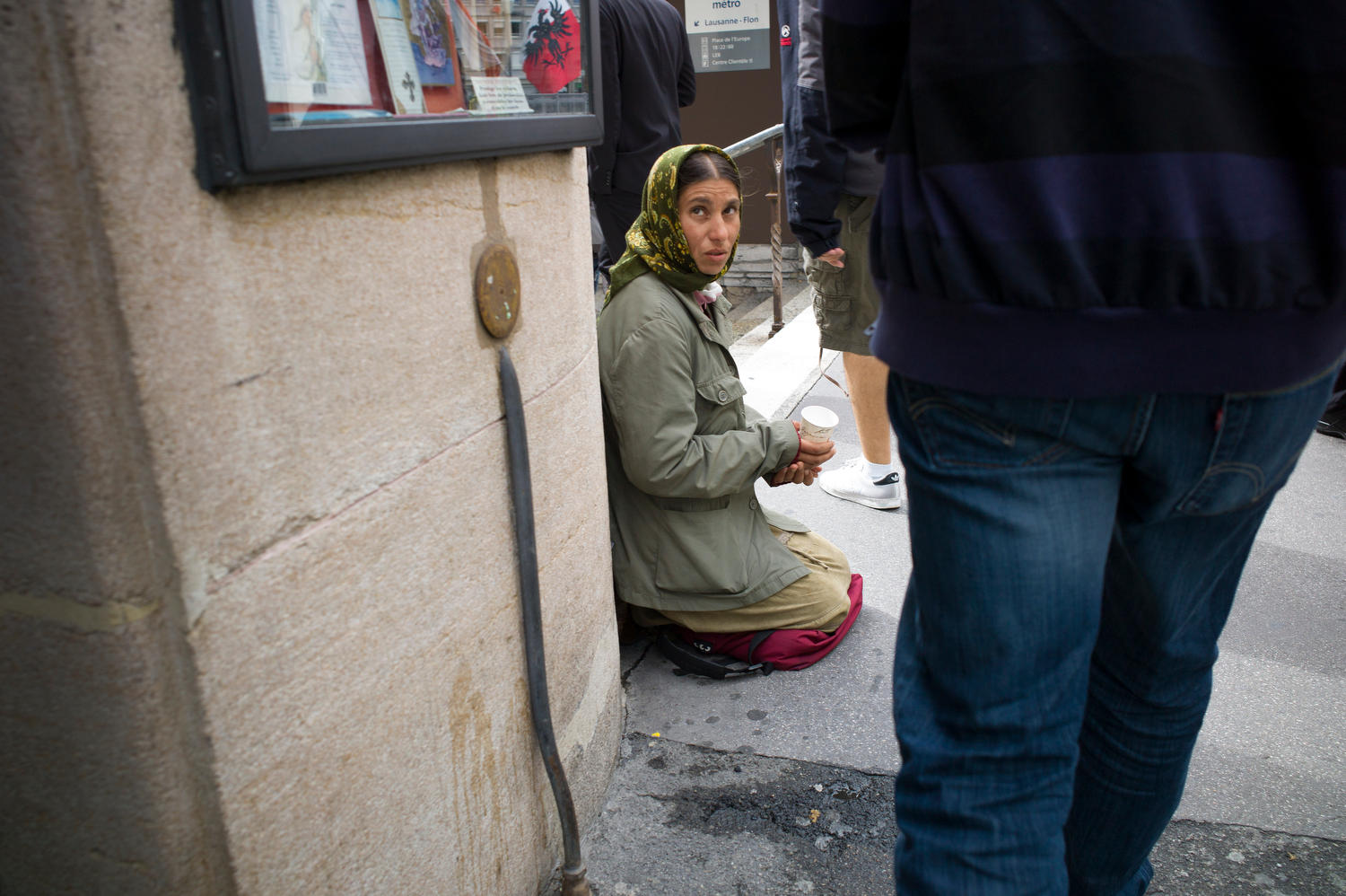 Una mujer sentada de rodillas mendiga en la calle