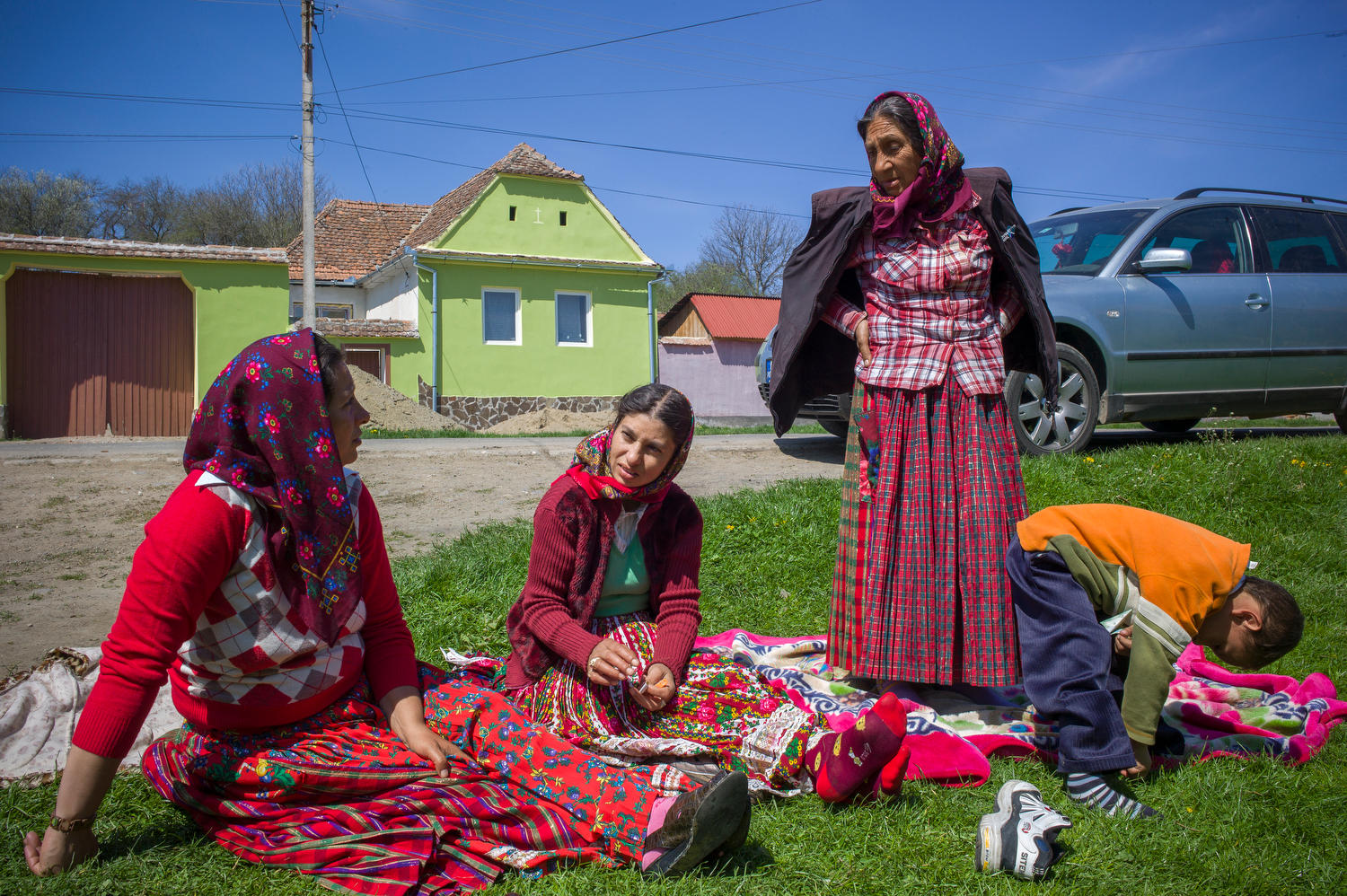Drei Frauen in farbigen Gewändern sitzen am Boden.