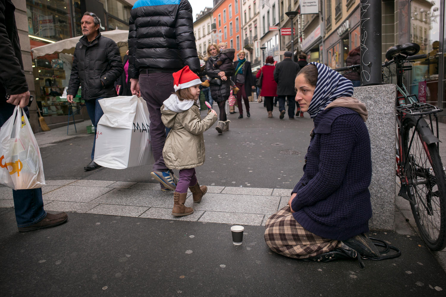 Una donna seduta per strada chiede la carità.