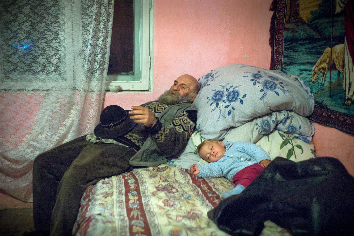 رجل ينام مستندا إلى سرير وبجانبه طفل