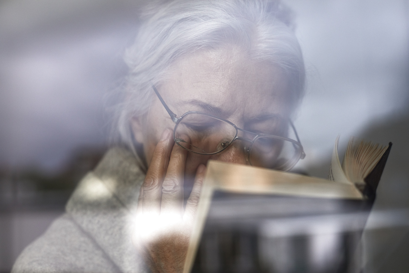 primo piano di donna anziana che legge un libro