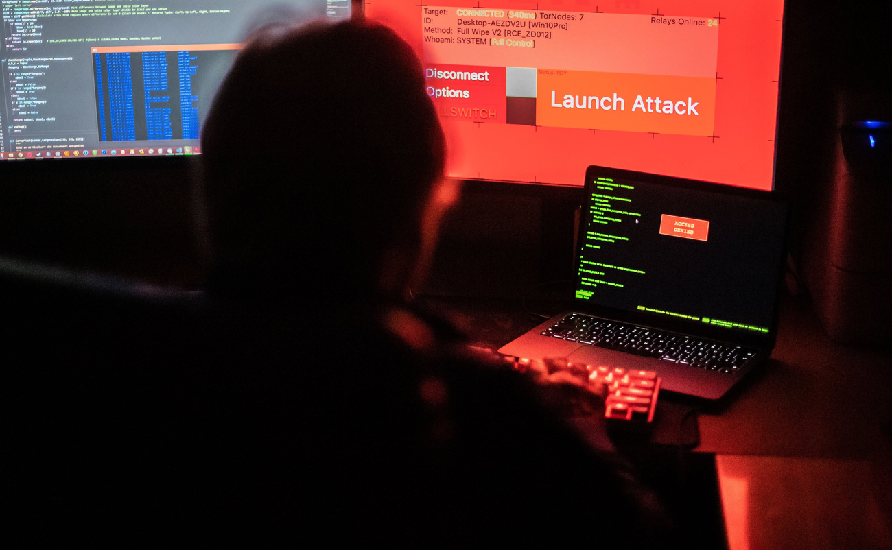 hacker davanti a schermi di computer