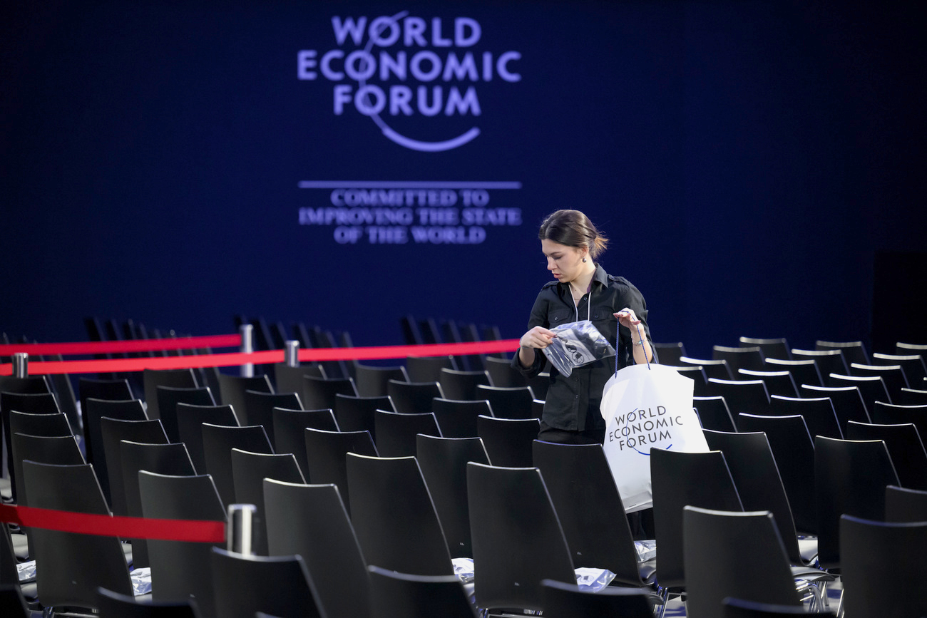 un teatro vacío con una mujer saliendo y de fondo el cartel del WEF