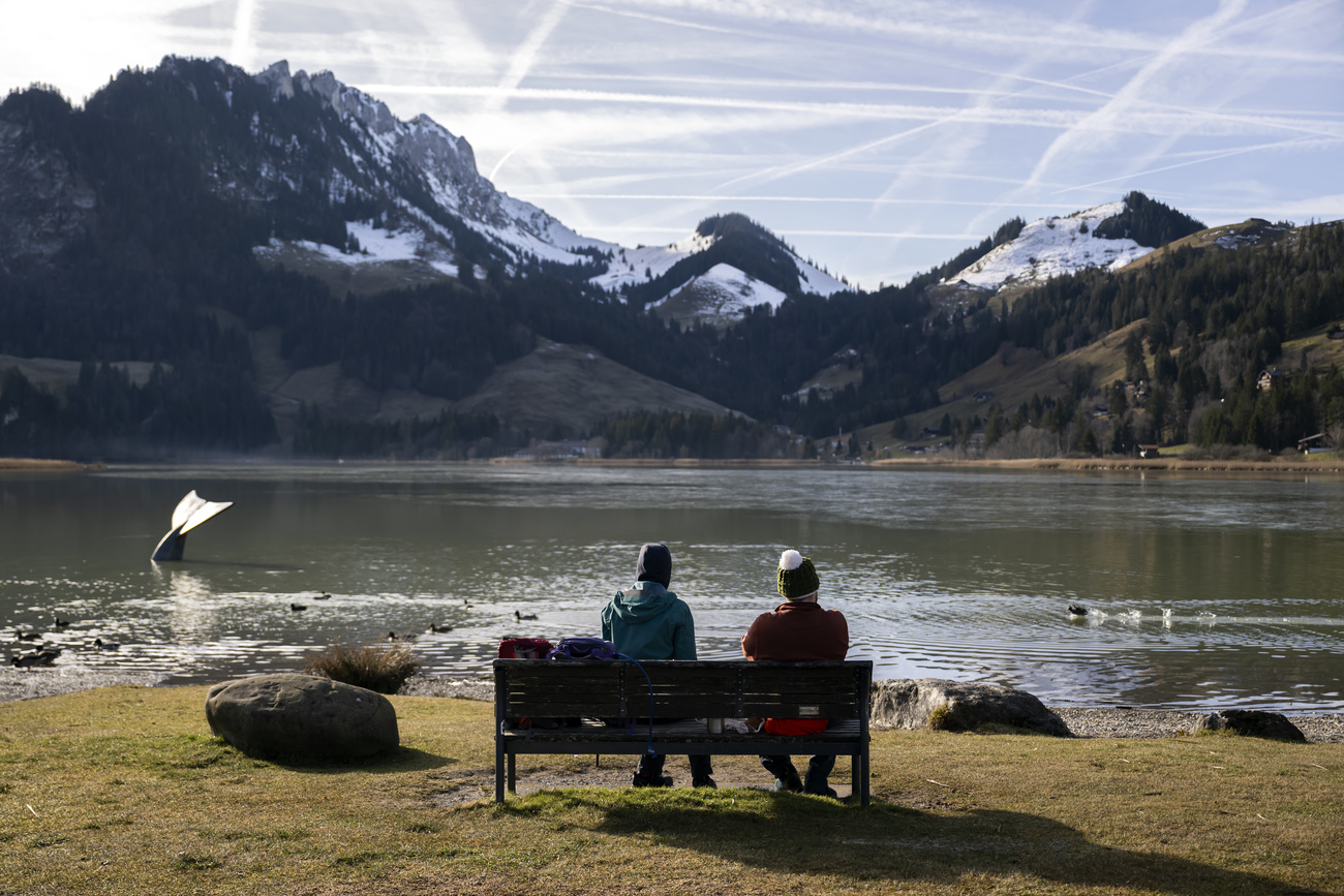 Ein Paar sitzt auf einer Bank und betrachtet die Berge und einen See