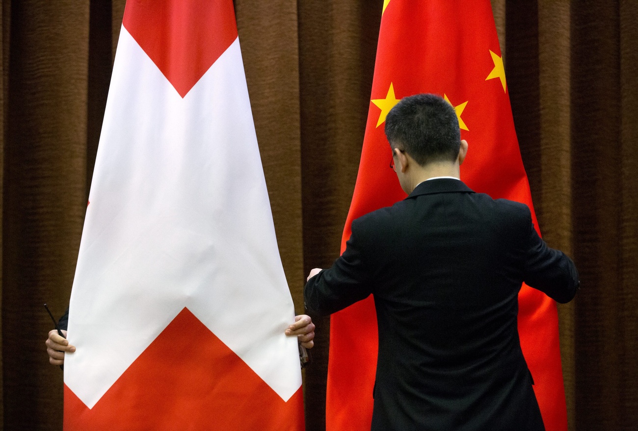 中国とスイスの国旗を整える男性