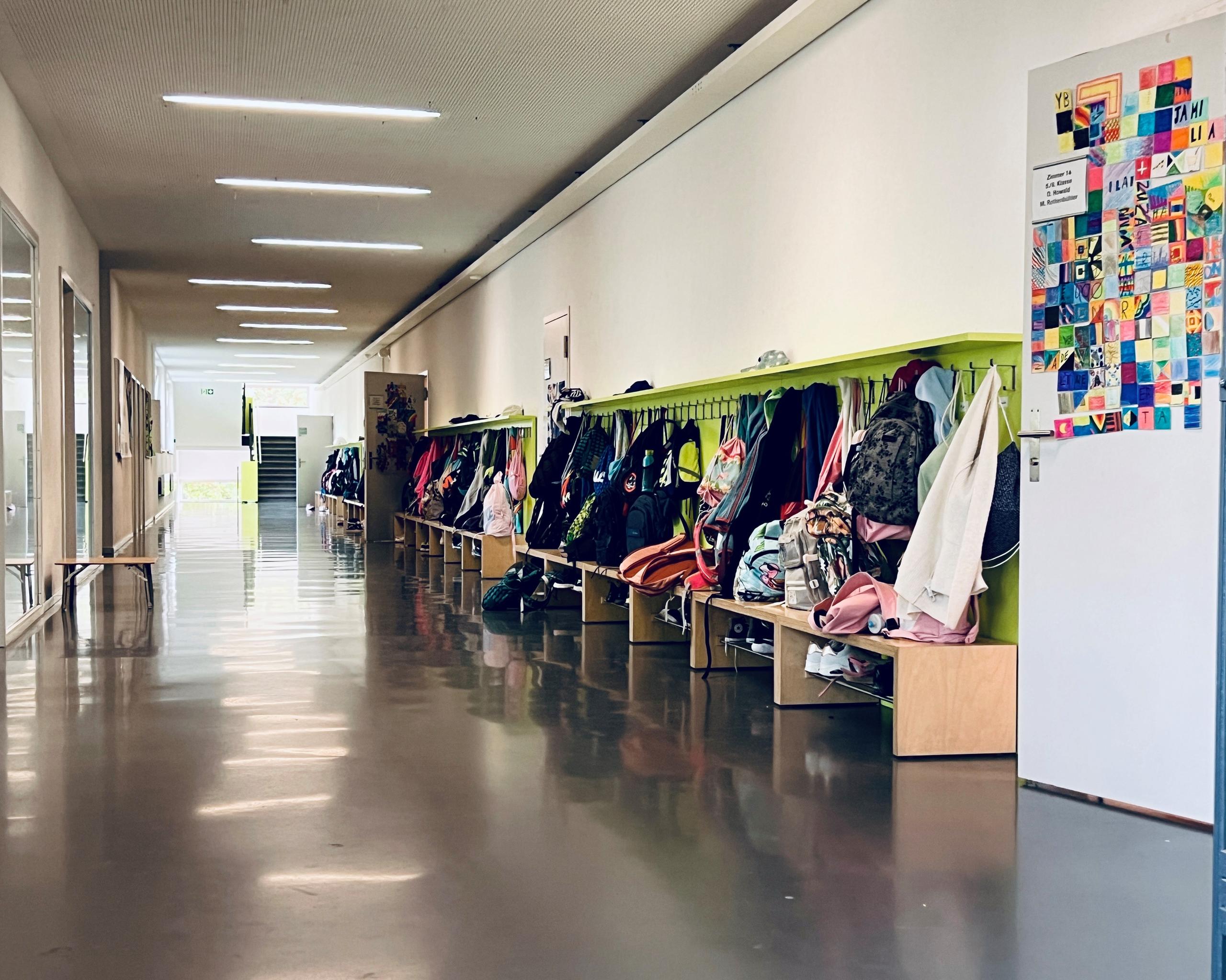 Korridor der Schule in Ittigen mit an der Garderobe hängenden Kinderjacken