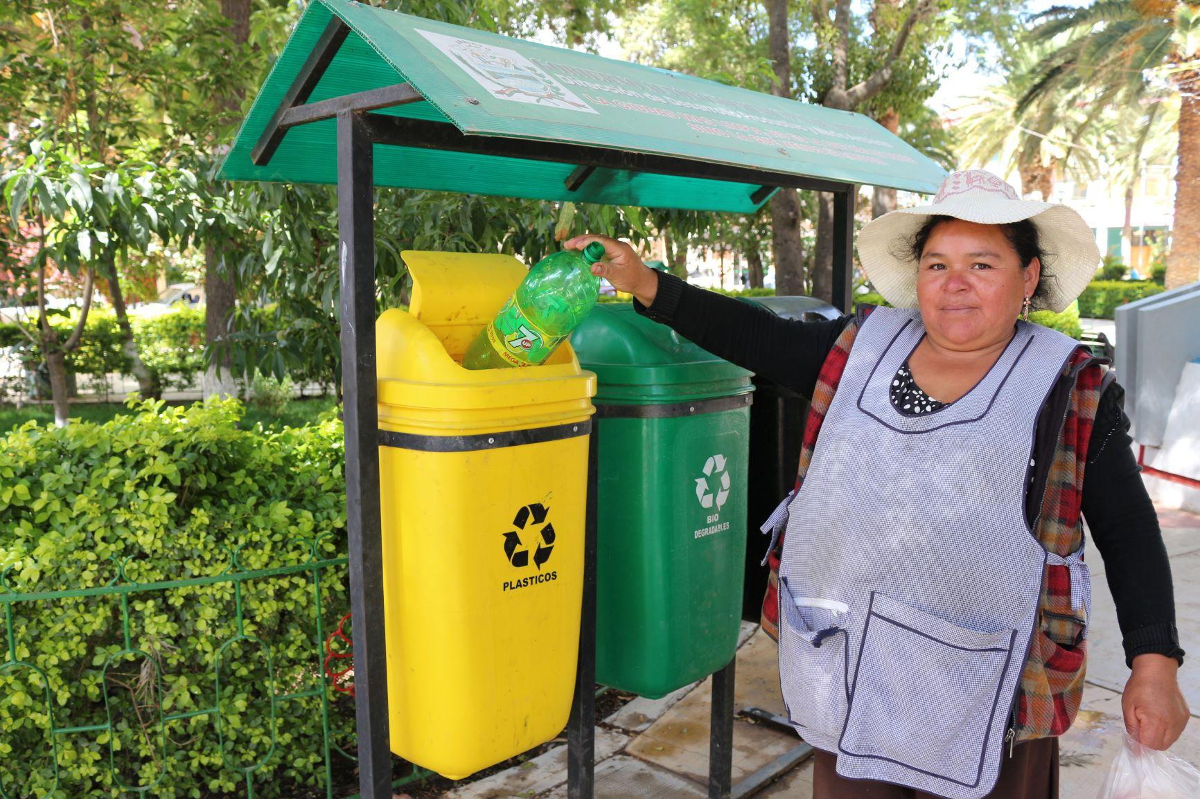 Una mujer tira un envase plástico en un basurero para pet