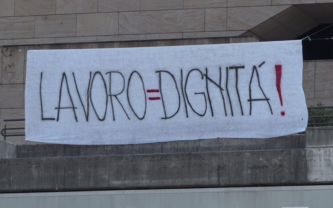 Uno striscione che cita lo slogan lavoro=dignità