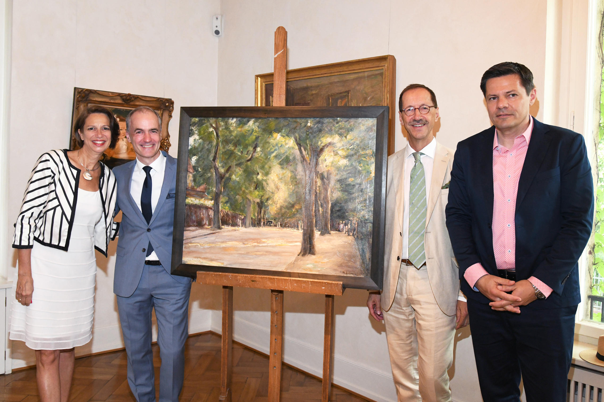 Al centro un quadro e quattro persone in piedi di fianco ai due lati.