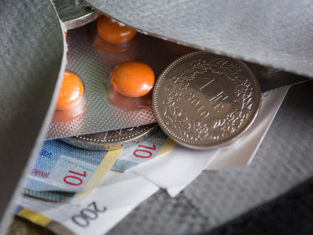 Blick in ein Portemonnaie, in dem Geld und Medikamente sind.