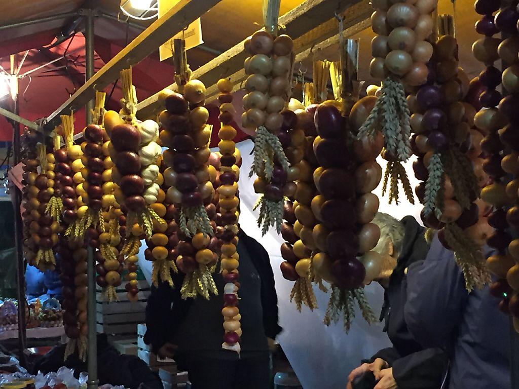 Zwiebelzöpfe sind an einem Stand aufgehängt.